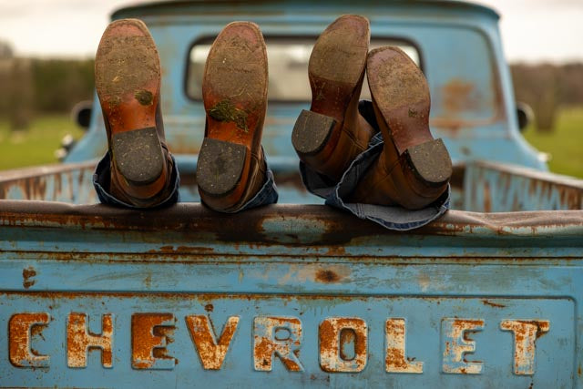 Cowboy boots resting on Chevrolet tailgate