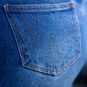 Close-up of a blue denim pocket with brand logo.