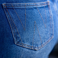Close-up of a blue denim pocket with brand logo.