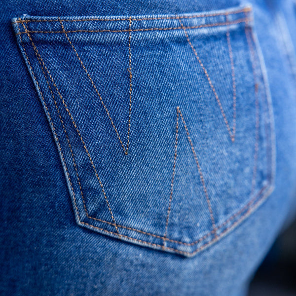 Close-up of a blue denim pocket with brand logo.