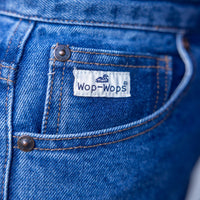 Close-up of blue denim jeans with a 'Wop-Wops' label on the pocket.