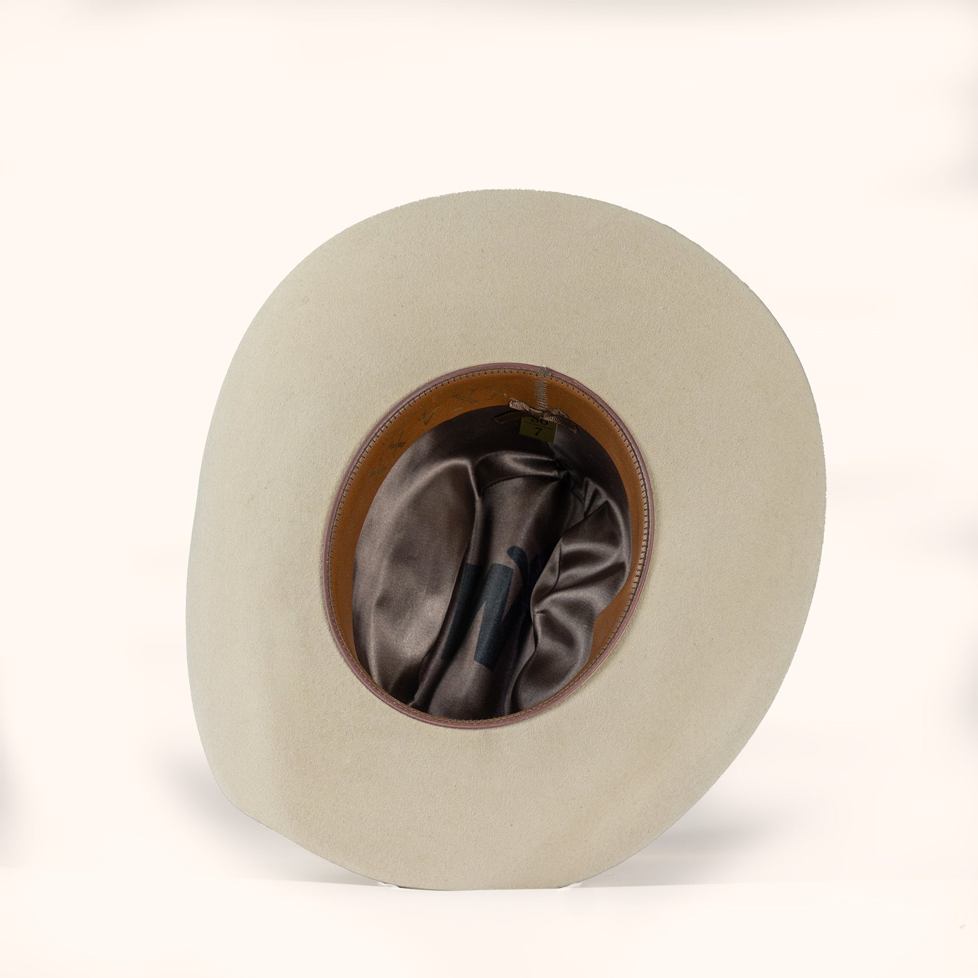 Beige cowboy hat with brown interior and leather sweatband on a white background