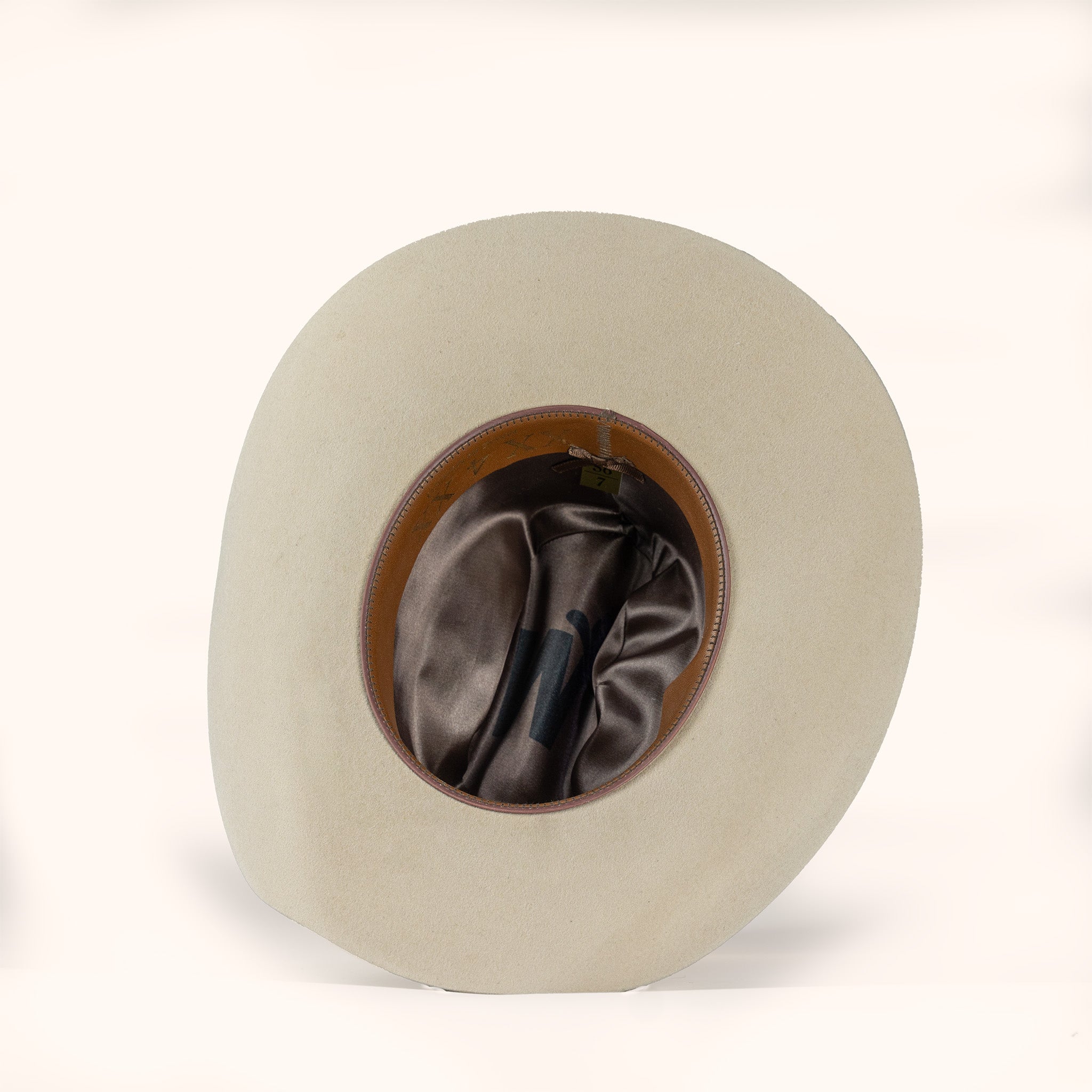 Beige cowboy hat with brown interior and leather sweatband on a white background